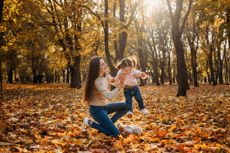 woman and child playing in autumn leaves