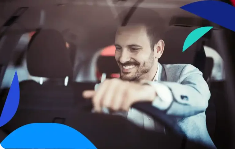 A man smiles while sitting behind the wheel of a car