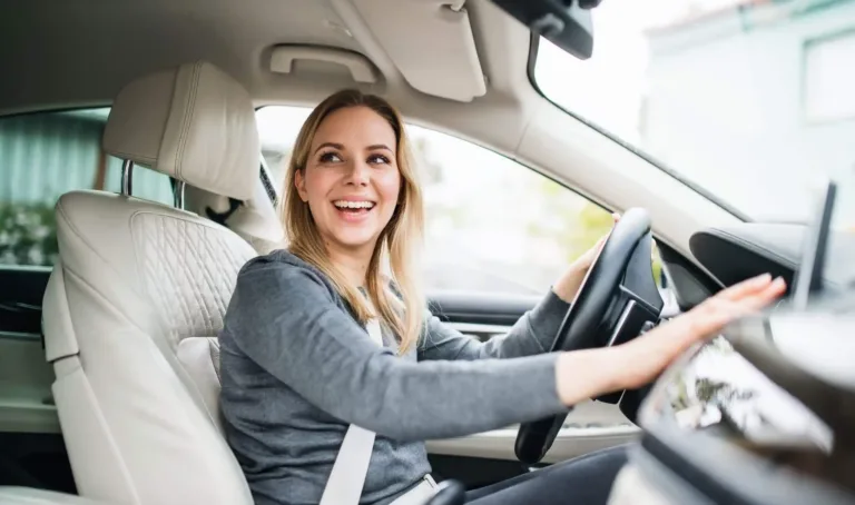 A woman smiles while sitting behind the wheel of a car